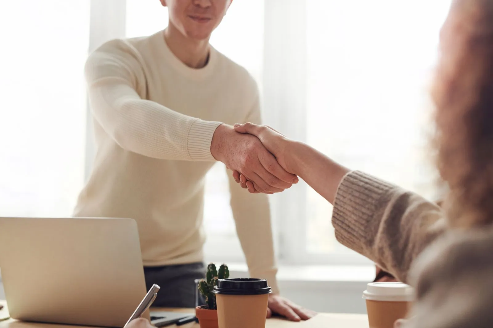 Deux entrepreneurs discutant autour d'un contrat et d'un ordinateur dans un espace de coworking.